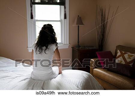 Stock Image - Woman sitting on edge of bed. Fotosearch