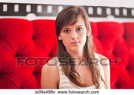 Stock Photo - Woman sitting on red sofa. Fotosearch