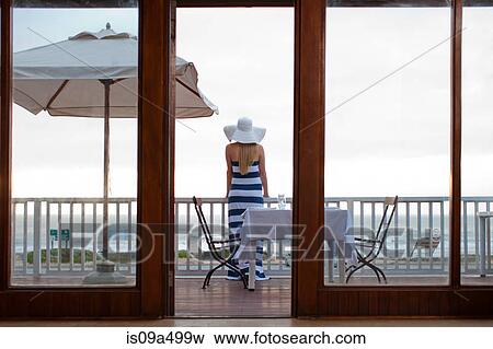 Woman standing on beachfront patio View Large Photo Image Stock Photo - Woman standing on beachfront patio. Fotosearch