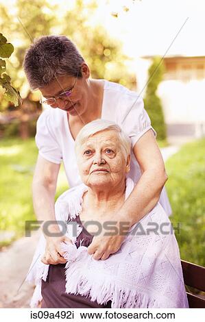 Stock Image - Woman tying shawl around friend. Fotosearch