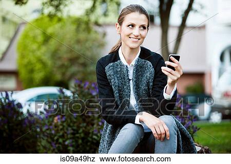 Woman using cell phone in urban park View Large Photo Image Stock Photo - Woman using cell phone in urban park. Fotosearch