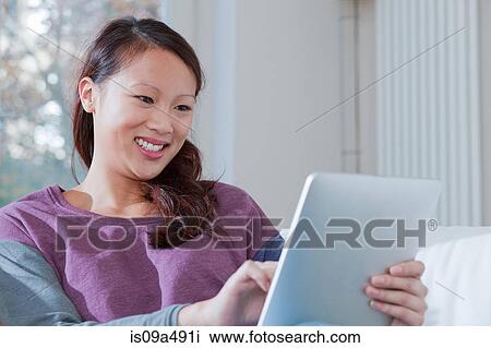 Woman using tablet computer on sofa View Large Photo Image Stock Image - Woman using tablet computer on sofa. Fotosearch