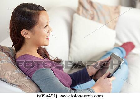 Woman using tablet computer on sofa View Large Photo Image Stock Image - Woman using tablet computer on sofa. Fotosearch