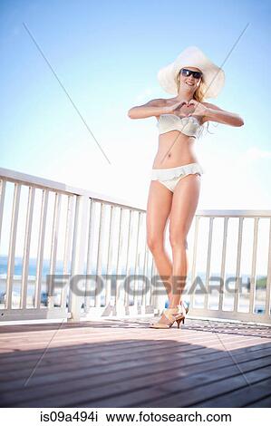 Stock Image - Woman wearing bikini on wooden deck. Fotosearch