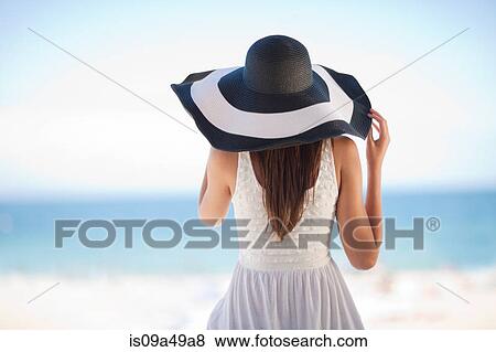 Stock Photo - Woman wearing floppy hat on beach. Fotosearch