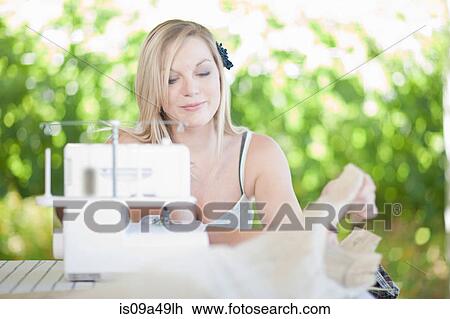 Stock Image - Woman working on sewing machine. Fotosearch
