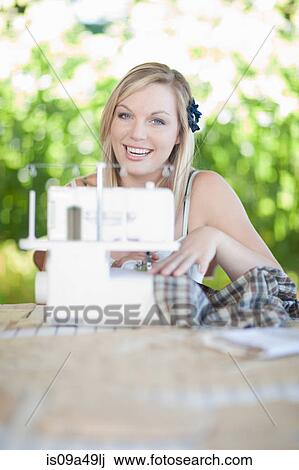 Stock Image - Woman working on sewing machine. Fotosearch