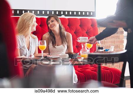 Stock Image - Women having breakfast together in cafe. Fotosearch