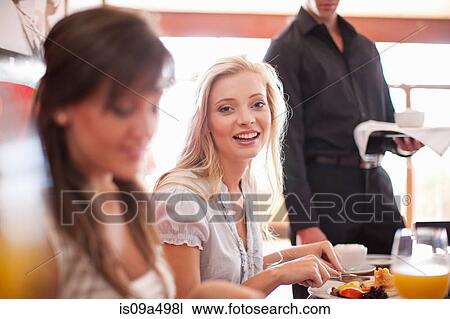 Stock Image - Women having breakfast together in cafe. Fotosearch