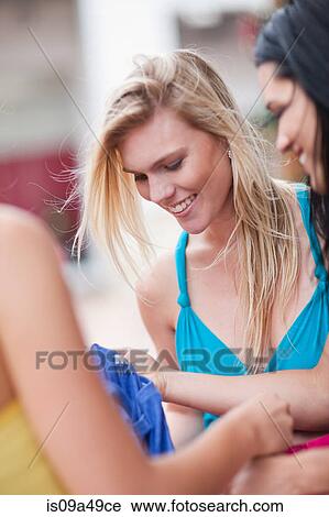 Stock Image - Women looking in shopping bags. Fotosearch