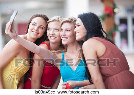 Stock Image - Women taking picture together outdoors. Fotosearch