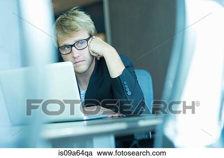 Stock Image - Bored businessman using laptop. Fotosearch