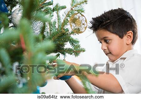 Boy decorating Christmas tree View Large Photo Image Stock Photo - Boy decorating Christmas tree. Fotosearch
