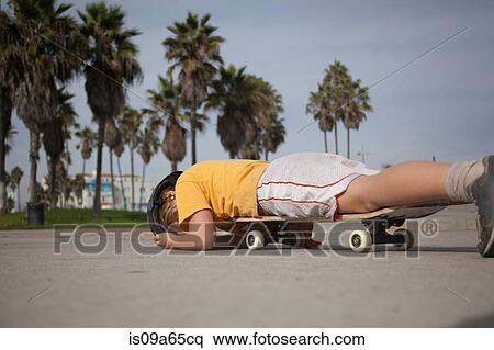 Stock Photography - Boy laying on skateboard in park. Fotosearch