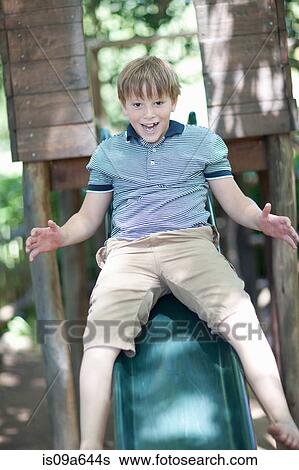 Stock Photograph - Boy playing on slide outdoors. Fotosearch