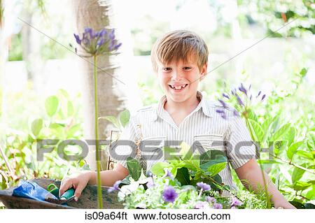 Stock Photograph - Boy potting plants outdoors. Fotosearch