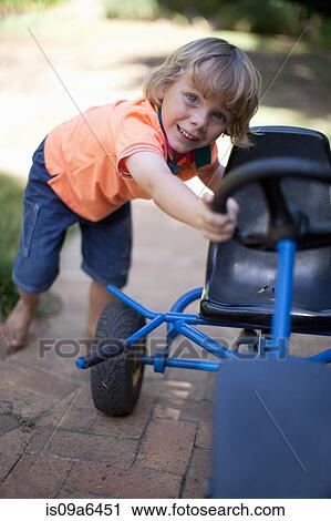 Boy pushing go kart outdoors View Large Photo Image Stock Image - Boy pushing go kart outdoors. Fotosearch