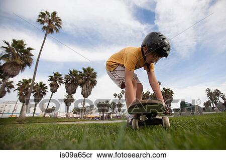 Boy putting skateboard in grass at park View Large Photo Image Stock Photography - Boy putting skateboard in grass at park. Fotosearch