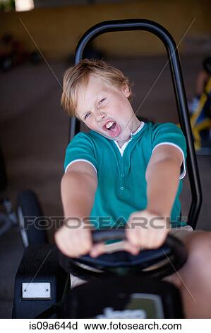 Stock Image - Boy riding go-kart in garage. Fotosearch