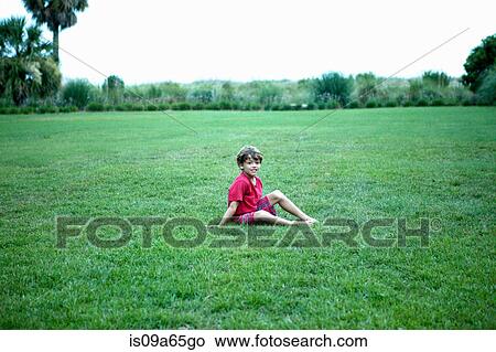 Picture - Boy sitting in grassy field. Fotosearch