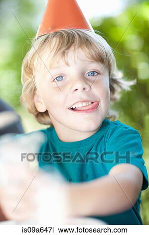 Stock Image - Boy wearing party hat outdoors. Fotosearch