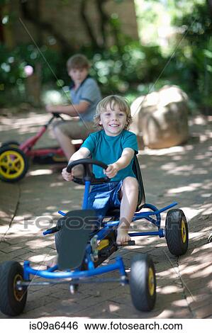 Stock Photograph - Boys riding go-kart on path. Fotosearch