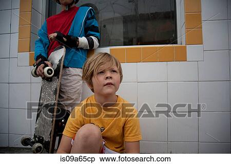 Stock Photography - Boys with skateboard sitting outdoors. Fotosearch