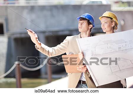 Stock Image - Business people reading blueprints. Fotosearch
