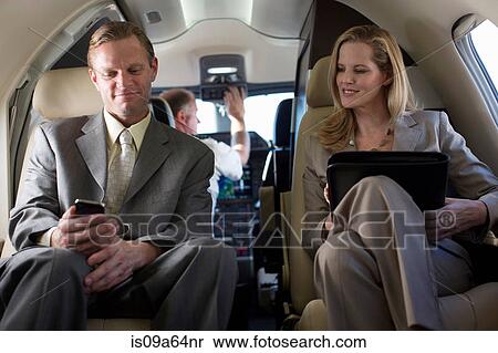 Stock Photography - Business people talking in airplane. Fotosearch