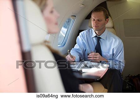 Businessman doing crossword on airplane View Large Photo Image Stock Image - Businessman doing crossword on airplane. Fotosearch