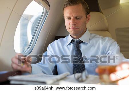 Businessman doing crossword on airplane View Large Photo Image Stock Image - Businessman doing crossword on airplane. Fotosearch
