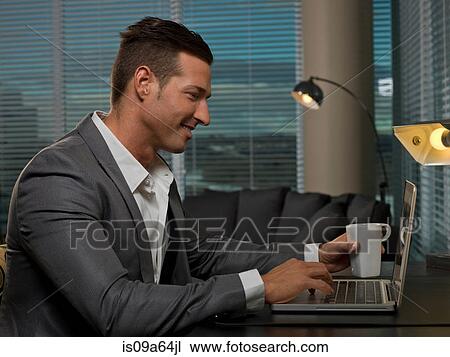 Stock Image - Businessman having cup of coffee at desk. Fotosearch