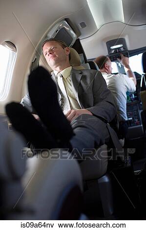 Businessman relaxing on airplane View Large Photo Image Stock Photo - Businessman relaxing on airplane. Fotosearch