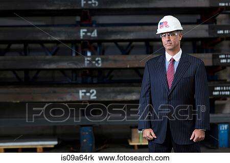 Stock Image - Businessman standing in metal plant. Fotosearch