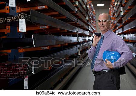Stock Image - Businessman standing in metal plant. Fotosearch