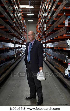 Stock Photo - Businessman standing in metal plant. Fotosearch
