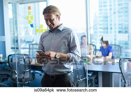 Businessman using cell phone in office View Large Photo Image Stock Image - Businessman using cell phone in office. Fotosearch