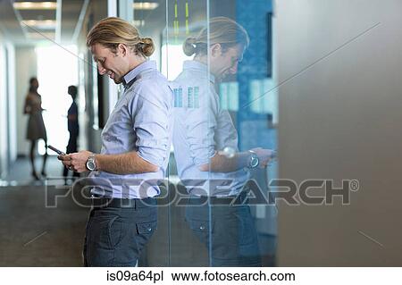 Stock Image - Businessman using cell phone in office. Fotosearch