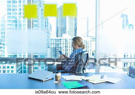 Businessman using cell phone in office View Large Photo Image Stock Photograph - Businessman using cell phone in office. Fotosearch