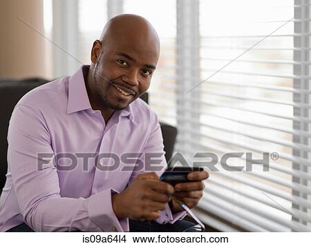 Businessman using cell phone on sofa View Large Photo Image Picture - Businessman using cell phone on sofa. Fotosearch