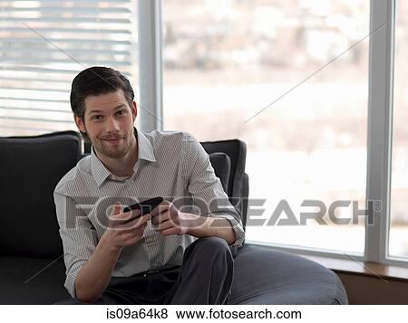 Businessman using cell phone on sofa View Large Photo Image Stock Photo - Businessman using cell phone on sofa. Fotosearch