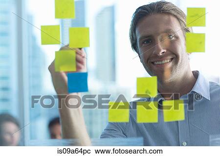 Stock Image - Businessman with sticky notes on window. Fotosearch