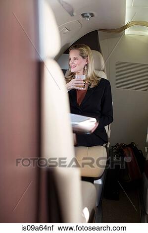 Stock Image - Businesswoman drinking on airplane. Fotosearch