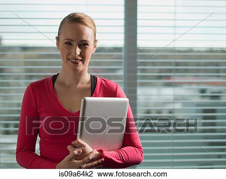 Businesswoman holding laptop by window View Large Photo Image Stock Image - Businesswoman holding laptop by window. Fotosearch