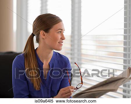 Stock Photography - Businesswoman reading newspaper on sofa. Fotosearch