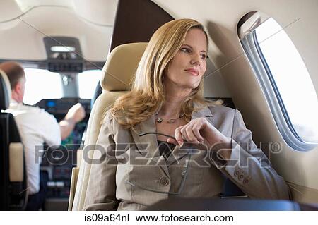 Stock Image - Businesswoman sitting in airplane. Fotosearch