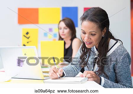 Stock Photo - Businesswoman taking notes at desk. Fotosearch