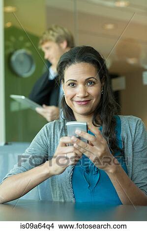 Picture - Businesswoman using cell phone in office. Fotosearch