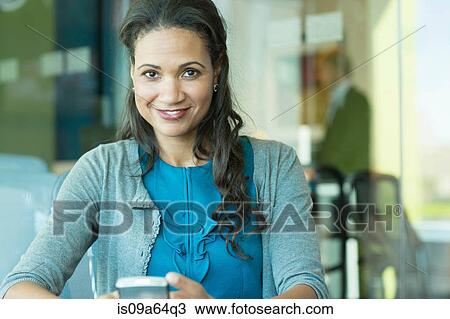 Stock Image - Businesswoman using cell phone in office. Fotosearch