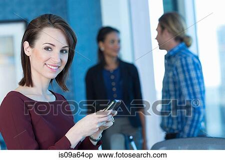 Stock Photography - Businesswoman using cell phone in office. Fotosearch